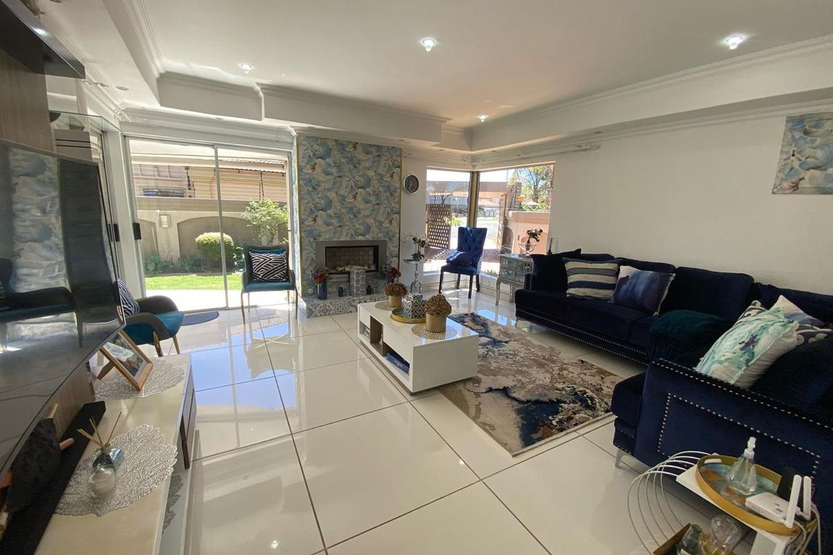 Spacious living room featuring large format polished floor tiles, a decorative fireplace with feature tiling, and sliding glass doors leading to the garden.