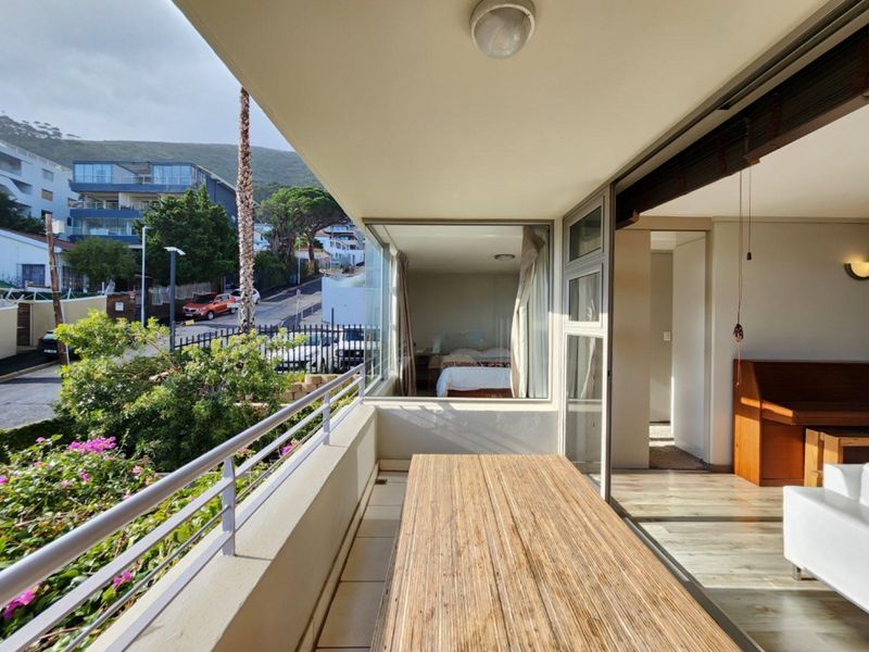 A covered balcony featuring tiled flooring and a metal balustrade, providing an outdoor extension to the interior living space.