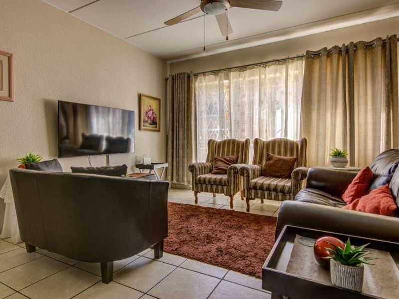 A comfortable living room featuring tiled flooring, a ceiling fan, and a large sliding glass door that provides natural light.