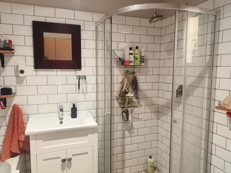 A functional bathroom featuring a white vanity cabinet, subway tile wall finishes, and a modern curved glass shower enclosure.