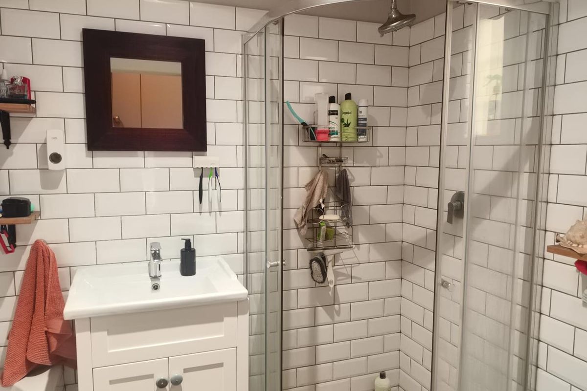 A functional bathroom featuring a white vanity cabinet, subway tile wall finishes, and a modern curved glass shower enclosure.