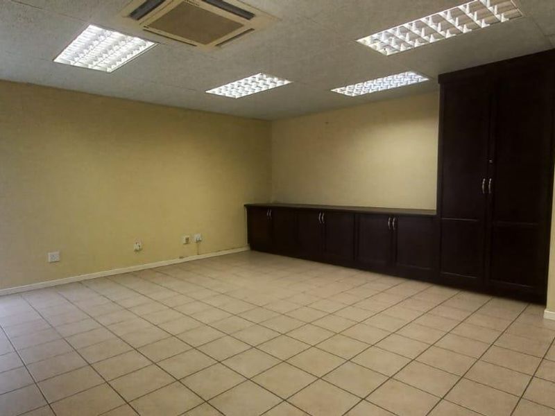 Spacious office area featuring tiled flooring, built-in storage cabinetry, recessed ceiling lighting, and a ceiling-mounted air conditioning unit.