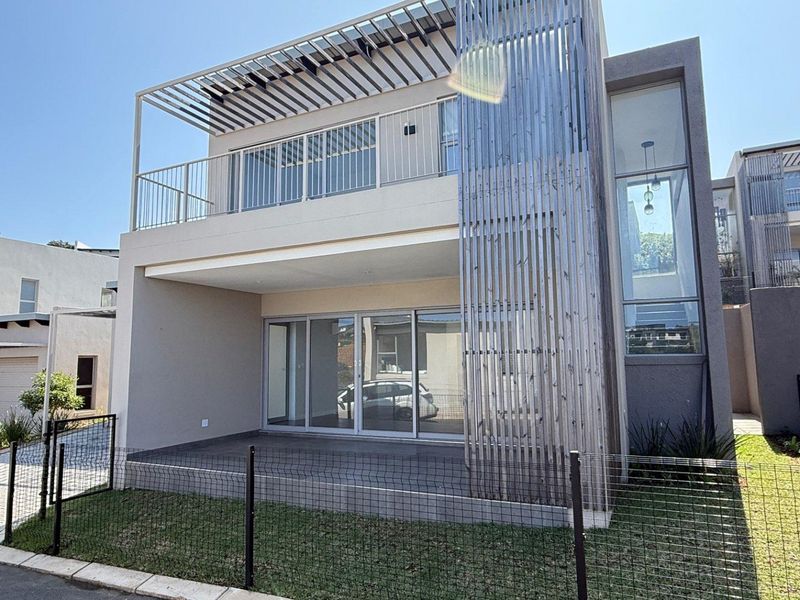 Modern townhouse exterior featuring a timber slat screen, upper-level balcony with pergola, and a ground-floor patio with sliding glass doors.