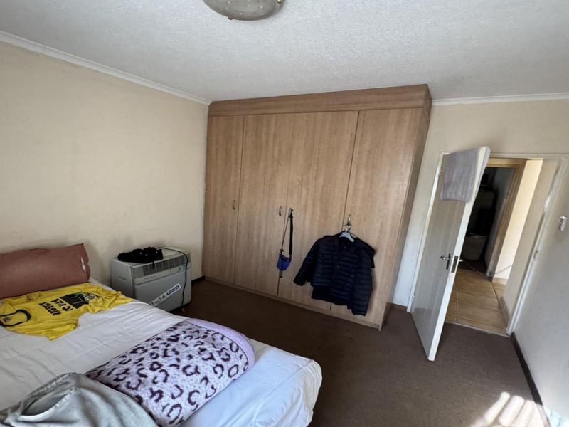 A bedroom featuring a large built-in wooden wardrobe, carpeted flooring, and coved ceiling details.