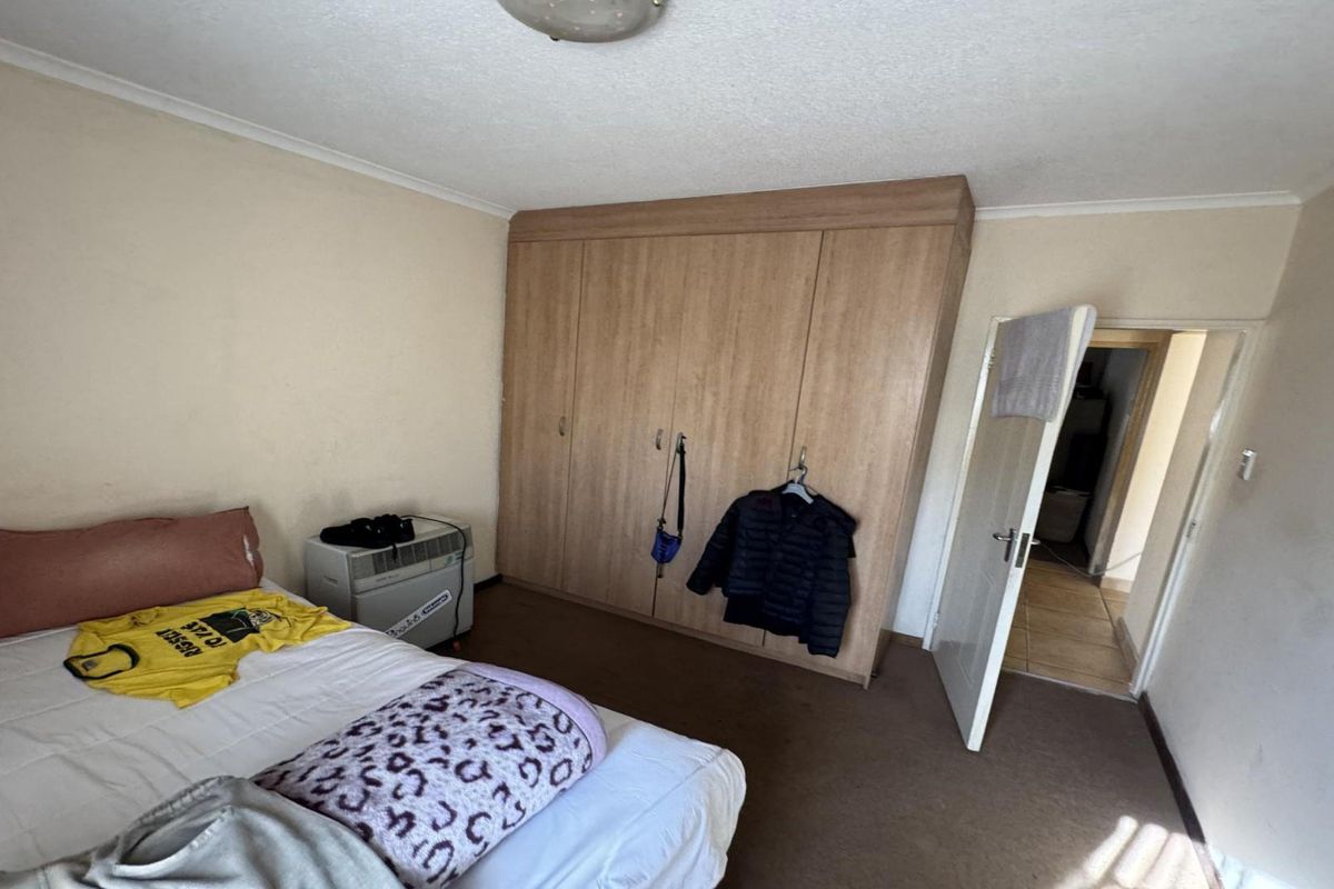 A bedroom featuring a large built-in wooden wardrobe, carpeted flooring, and coved ceiling details.