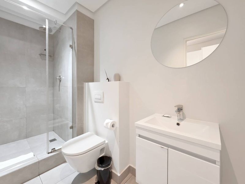 Modern bathroom featuring a walk-in shower with glass enclosure, wall-hung toilet with concealed cistern, and a sleek vanity unit with basin.