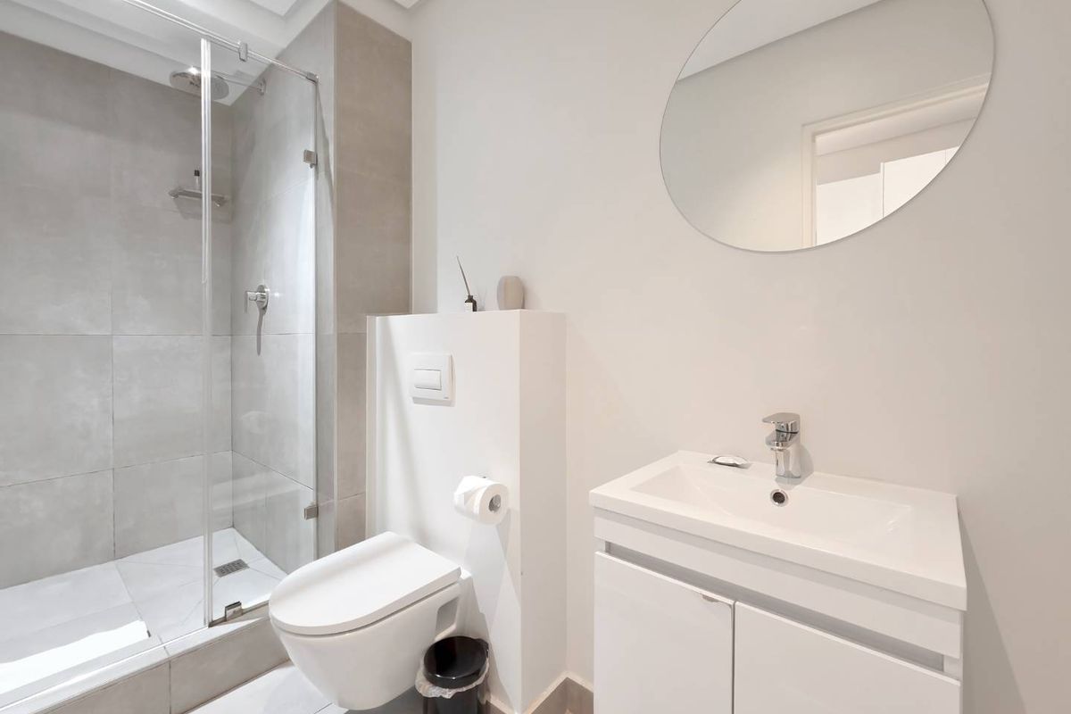 Modern bathroom featuring a walk-in shower with glass enclosure, wall-hung toilet with concealed cistern, and a sleek vanity unit with basin.