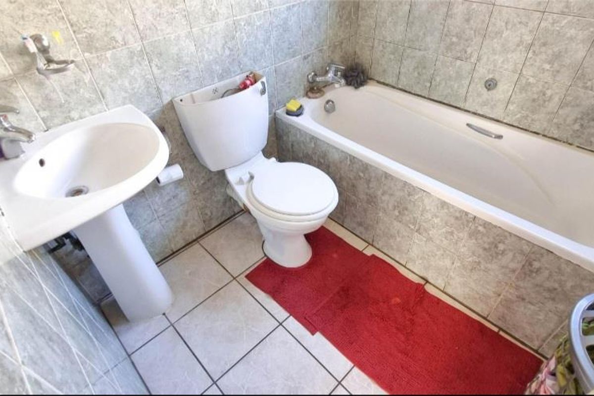 A compact bathroom featuring a pedestal basin, standard toilet, and a built-in bathtub with tiled surround.