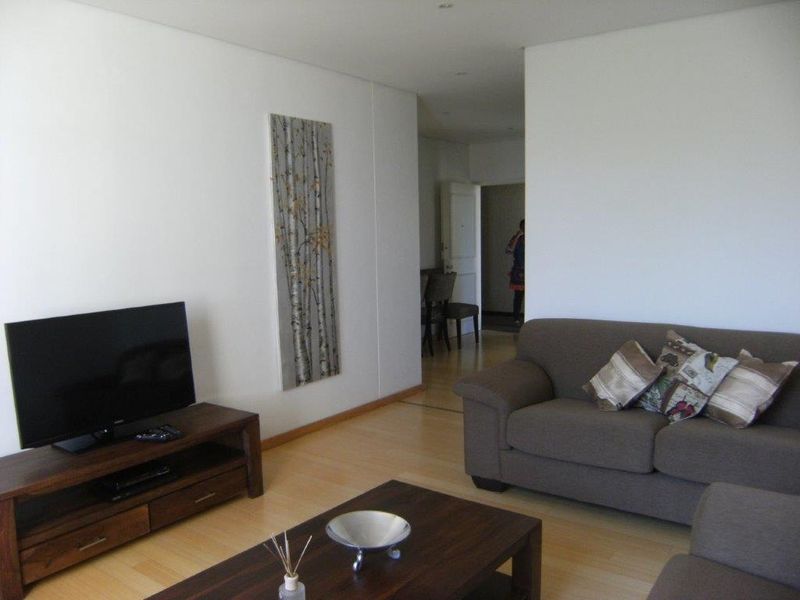 A living room featuring light-toned laminate flooring and neutral walls, providing a functional and well-lit space for relaxation.