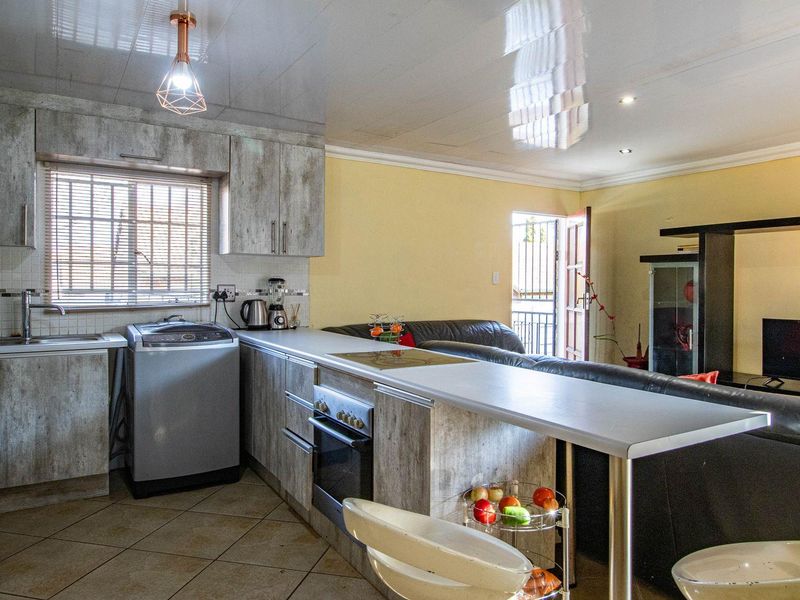 Open-plan kitchen and living area featuring wood-look cabinetry, built-in oven, hob, and a breakfast bar counter.