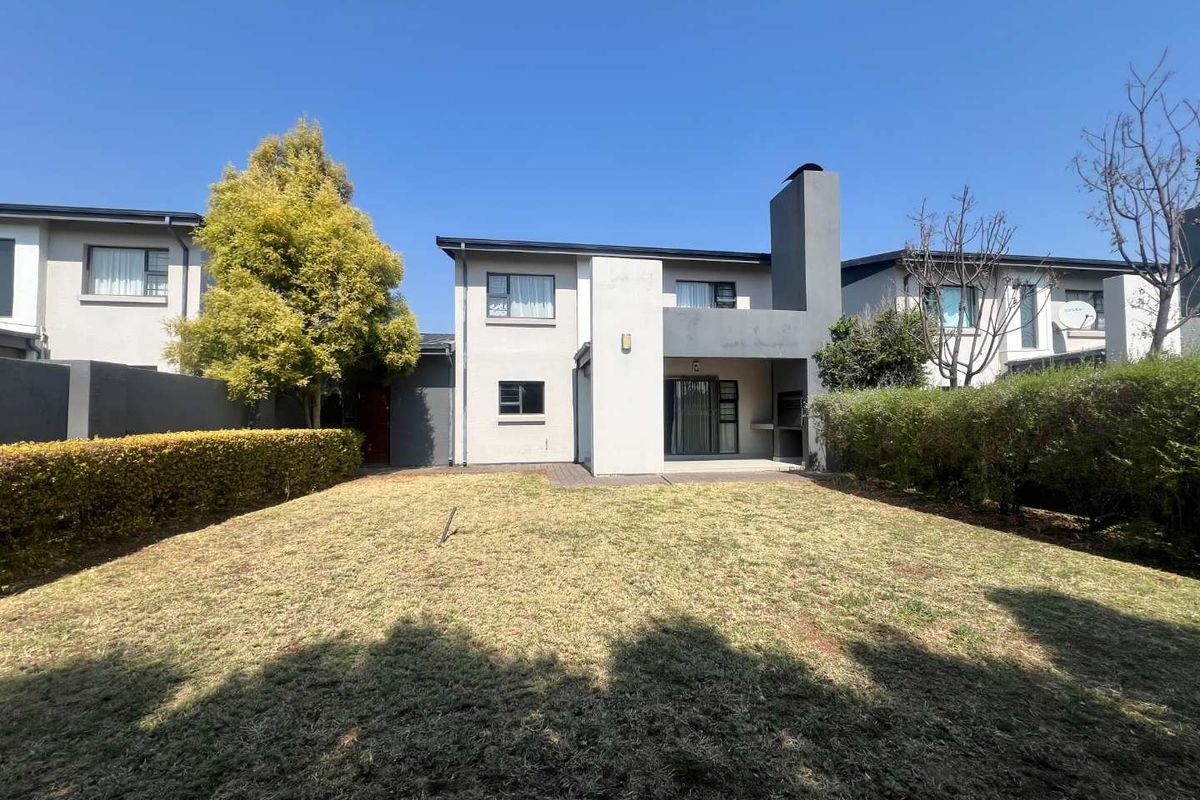 Rear view of the cluster property featuring a private garden, paved patio area, and a built-in outdoor braai facility.