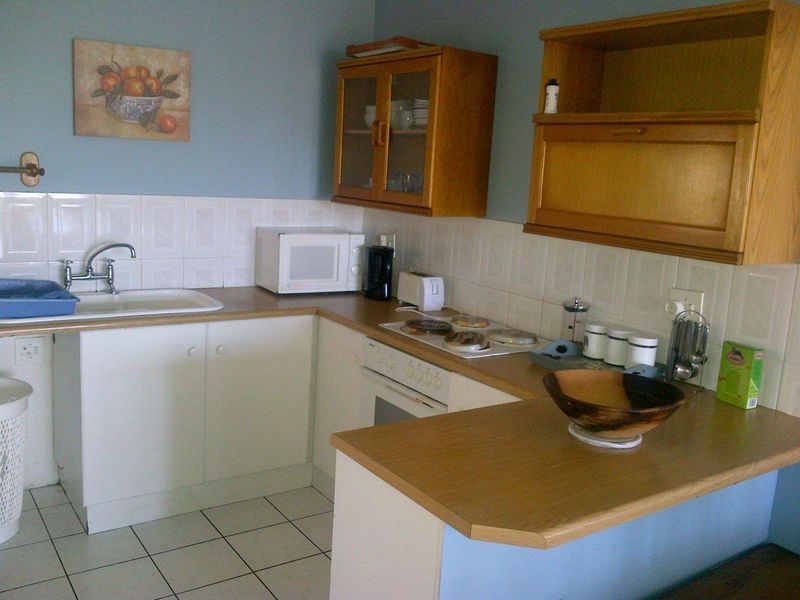 A functional kitchen featuring white cabinetry, laminate countertops, tiled backsplash, and built-in cooking appliances with a breakfast bar area.