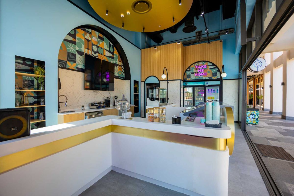 Modern commercial service counter area featuring integrated refrigeration, stylish decorative wall paneling, and recessed ceiling lighting in a well-maintained retail space.