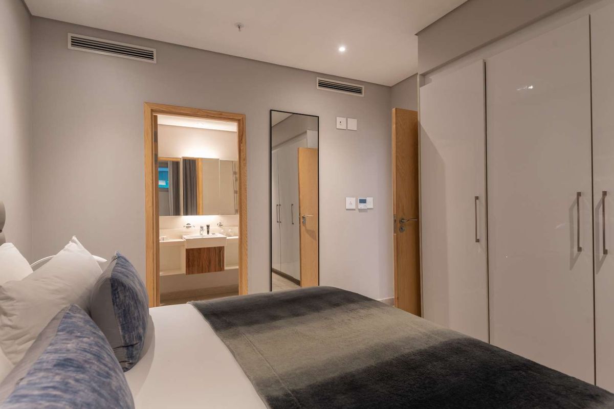Modern bedroom featuring built-in wardrobes, ducted air conditioning, and direct access to a well-appointed en-suite bathroom with contemporary finishes.