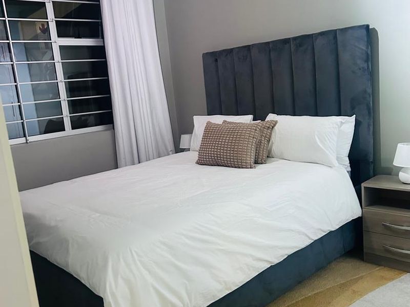 A well-maintained bedroom featuring a window with security bars and neutral wall finishes.