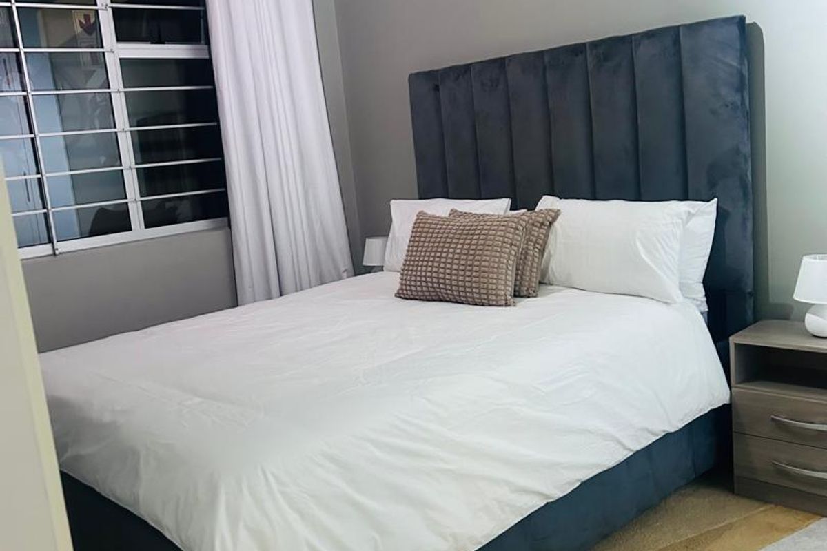 A well-maintained bedroom featuring a window with security bars and neutral wall finishes.