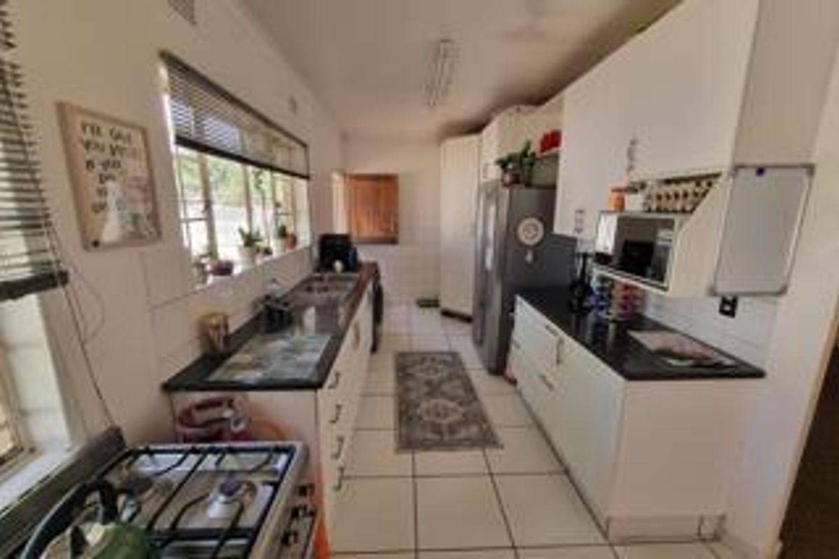 A functional kitchen featuring white cabinetry, dark countertops, a gas stove, and a double sink with tiled flooring throughout.