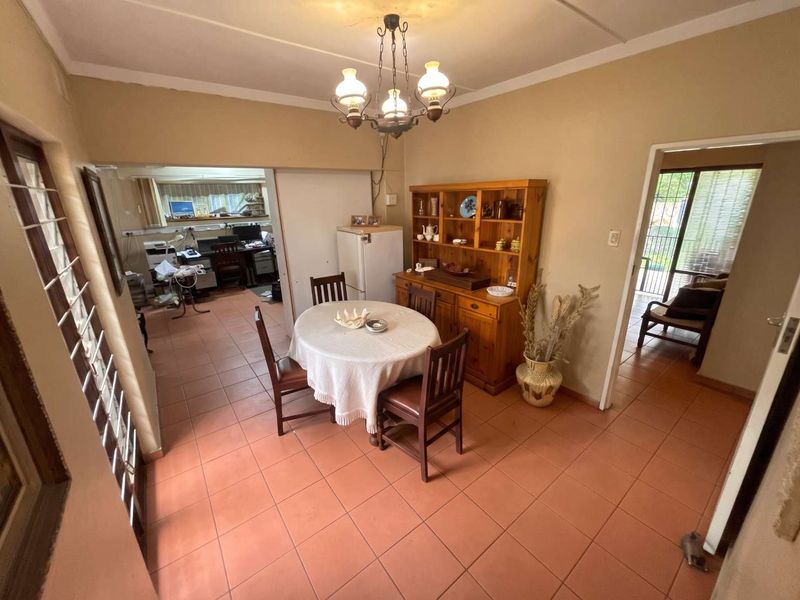 Dining area featuring tiled flooring and a central light fixture, with access to adjacent rooms and an outdoor patio area.