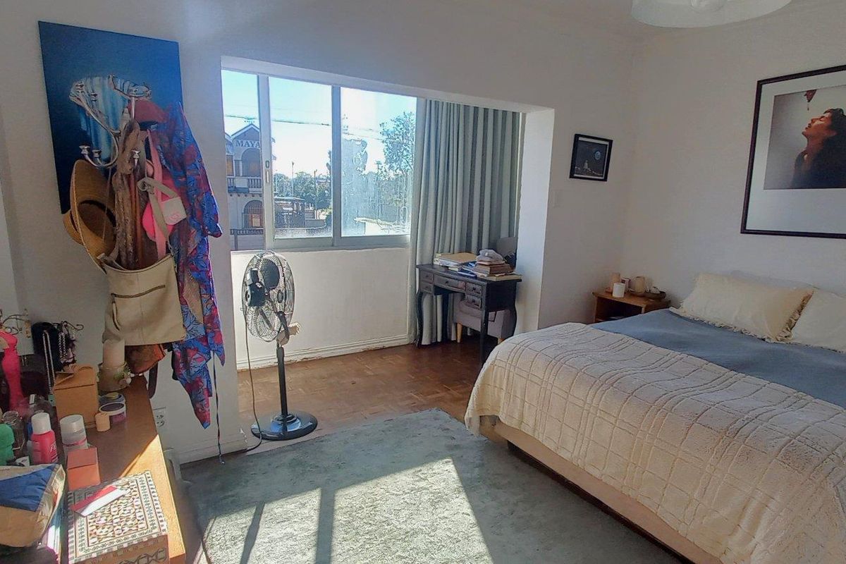 A bedroom featuring parquet flooring and a large window that allows for natural light, creating a bright and functional living space.