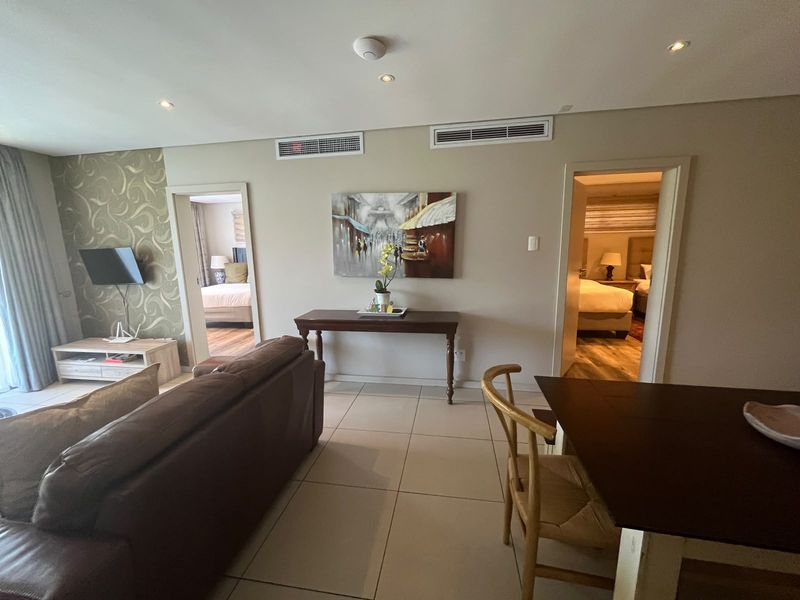 A well-maintained living area featuring tiled flooring, ducted air conditioning, and recessed lighting, with direct access to adjacent bedrooms.