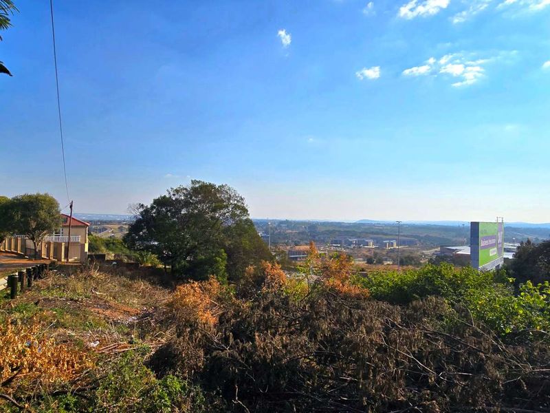 An elevated view overlooking the surrounding landscape, featuring a nearby road, guardrail, and a large billboard in the distance.