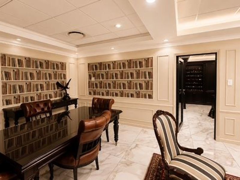 Elegant office space featuring sophisticated wainscoting, marble flooring, coffered ceilings, and custom built-in shelving, creating a refined and professional atmosphere.