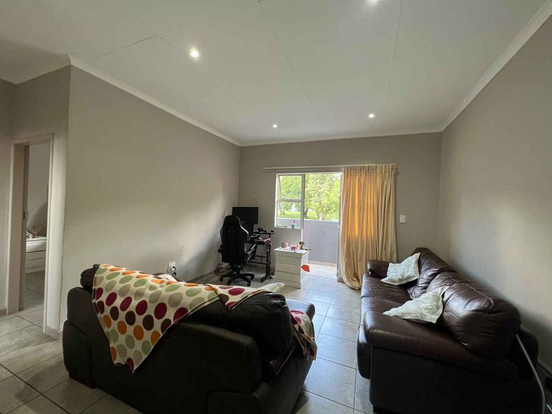 A living room featuring tiled flooring, recessed downlighting, and a sliding glass door providing access to an outdoor balcony area.