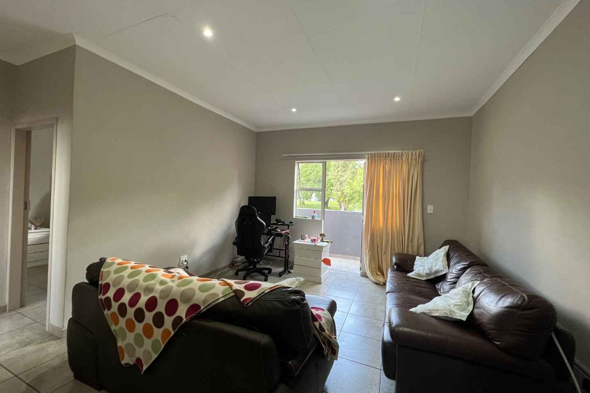 A living room featuring tiled flooring, recessed downlighting, and a sliding glass door providing access to an outdoor balcony area.