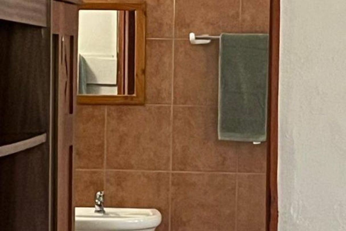 A view into a bathroom featuring a pedestal sink, tiled walls, and a wall-mounted towel rail.