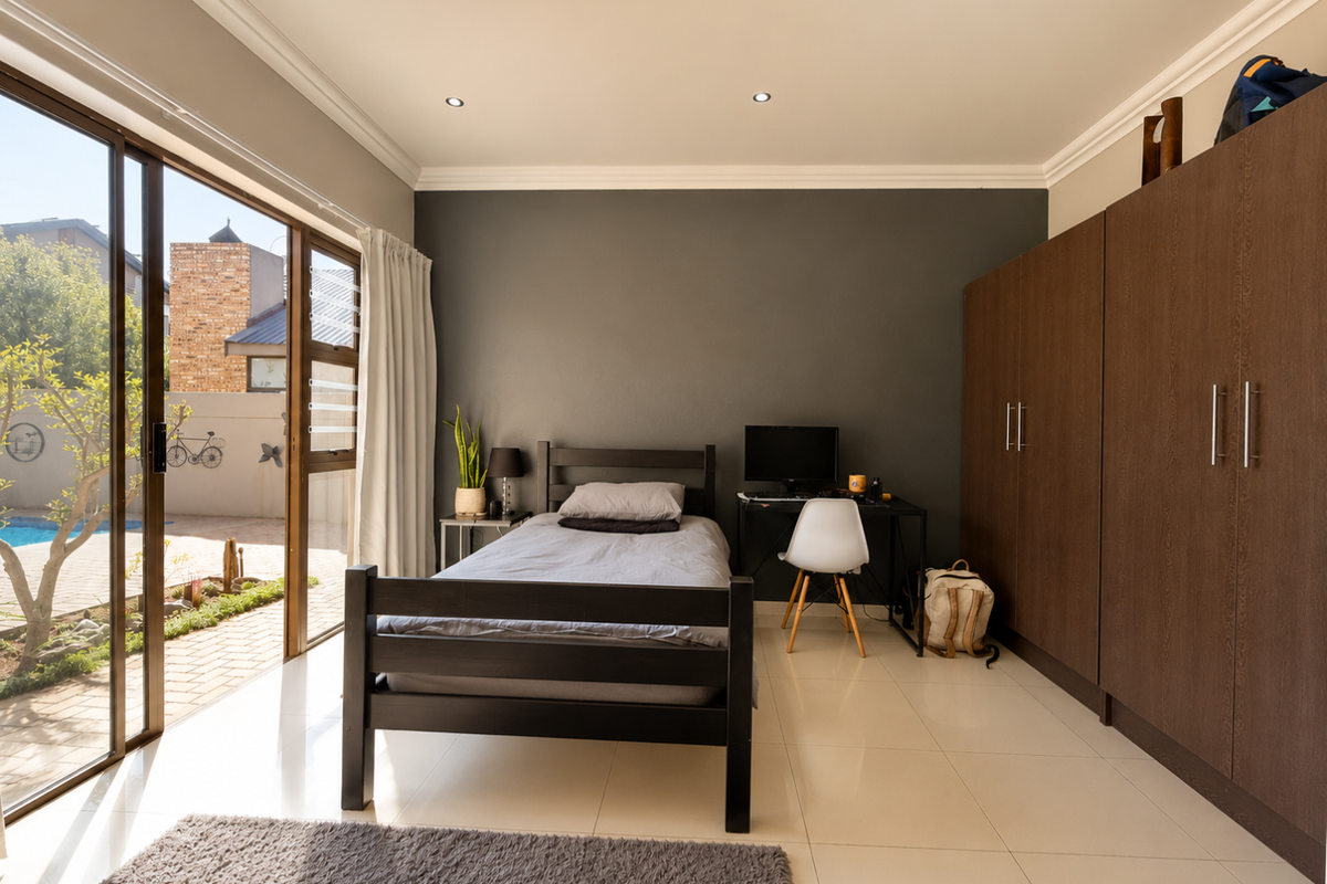 A well-lit bedroom featuring tiled floors, built-in cupboards, and a large sliding glass door providing direct access to the outdoor pool area.