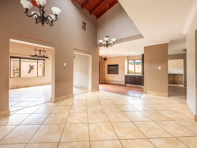 Spacious open-plan living area featuring high vaulted timber ceilings, tiled flooring, and a built-in fireplace, offering a versatile layout for modern living.