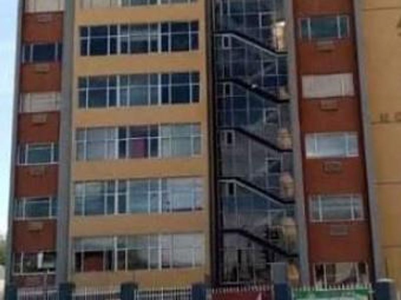 A multi-story office building facade featuring a prominent external staircase, glass curtain walling, and perimeter security fencing.