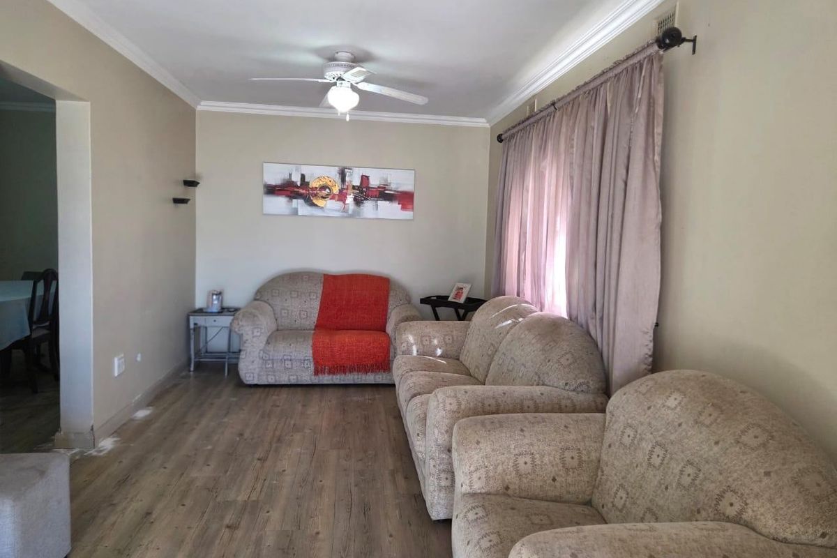 A living room featuring laminate flooring, crown molding, and a ceiling fan, offering a neutral base for potential interior updates.