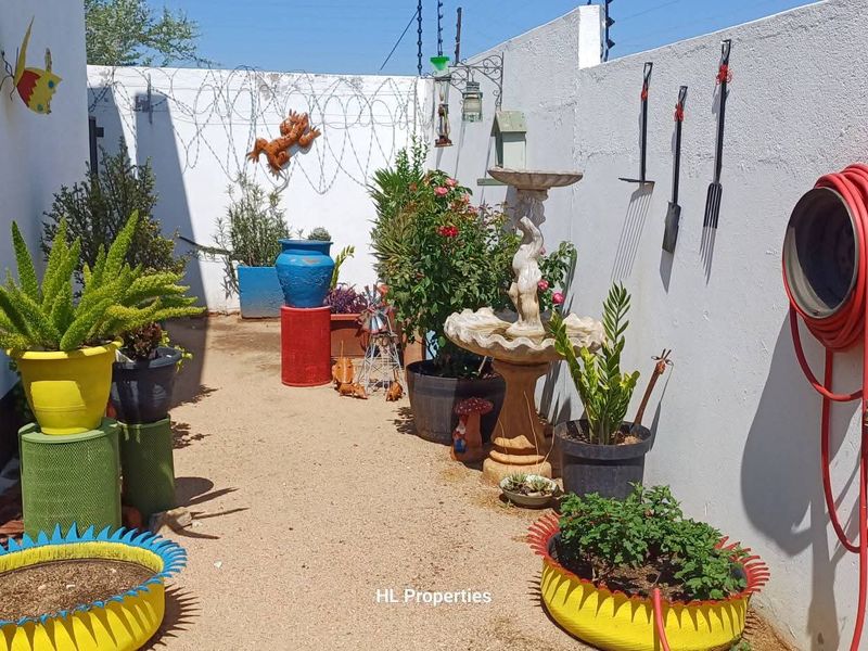 A private rear courtyard area featuring a perimeter wall with security spikes and an outdoor water tap.
