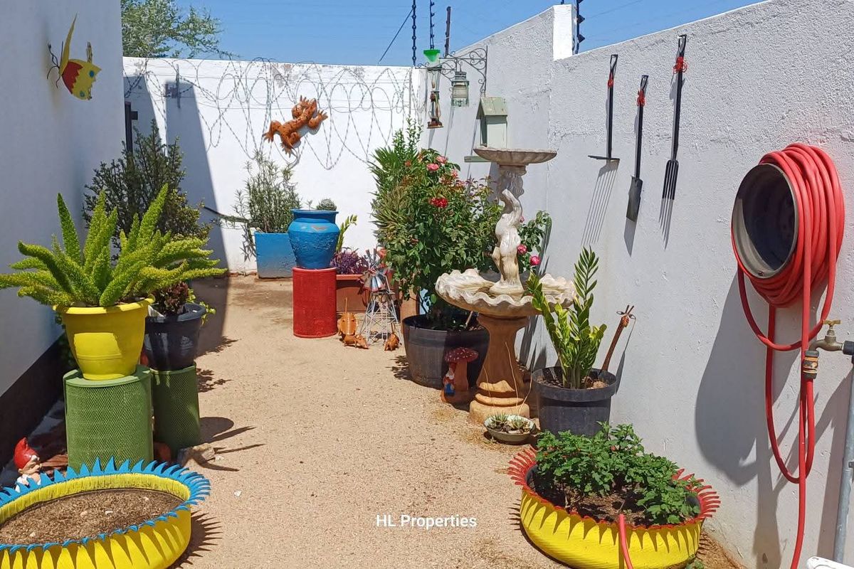 A private rear courtyard area featuring a perimeter wall with security spikes and an outdoor water tap.