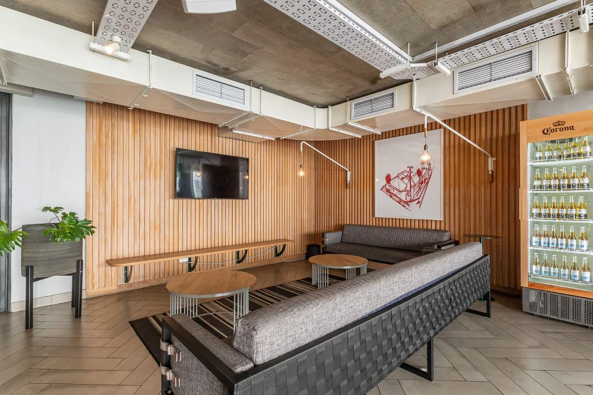 A modern lounge area featuring industrial-style exposed concrete ceilings, timber-slatted wall paneling, and tiled flooring, creating a contemporary and inviting atmosphere.