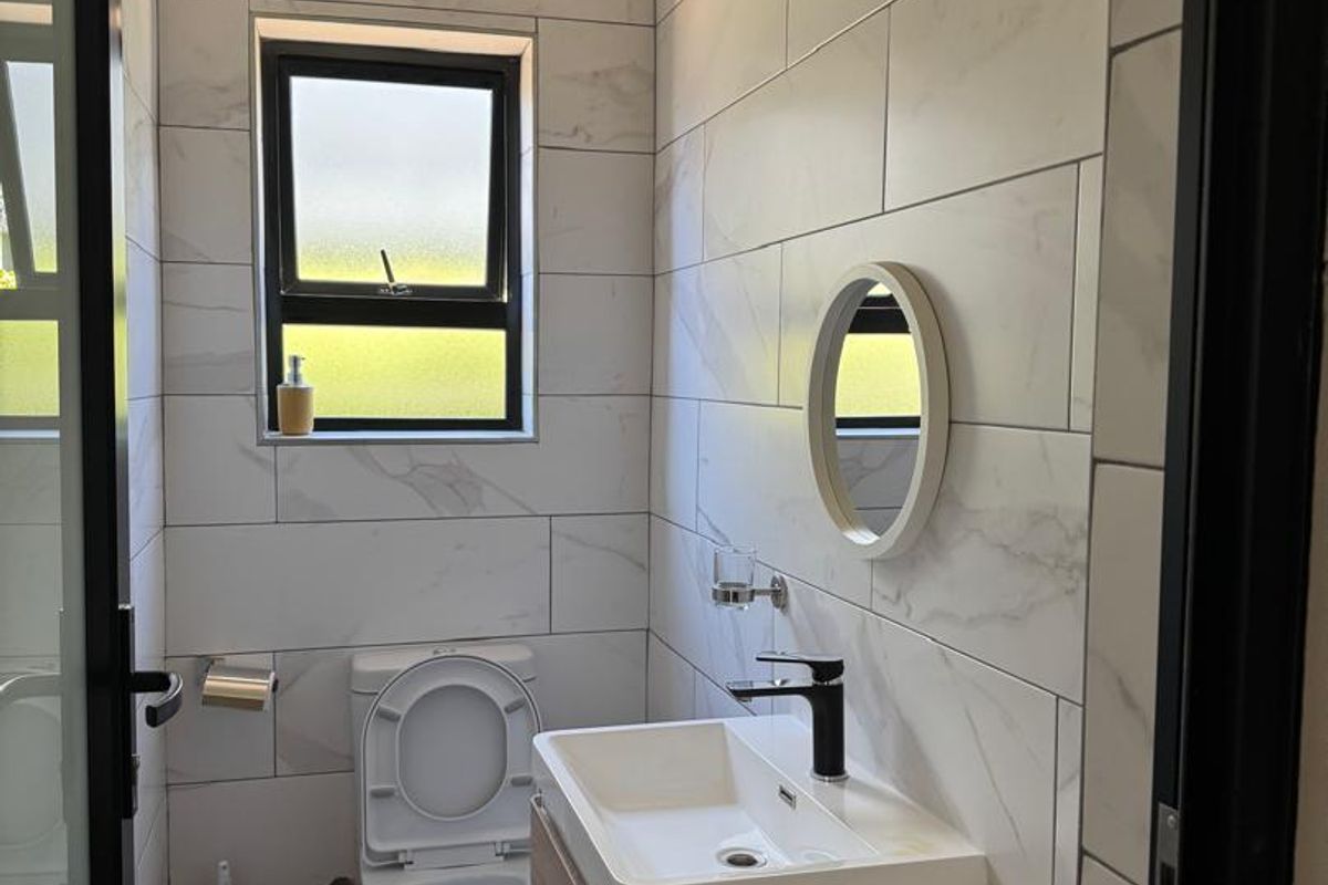 A modern, compact bathroom featuring floor-to-ceiling marble-look wall tiles, a wall-mounted vanity with a basin, and a contemporary toilet.