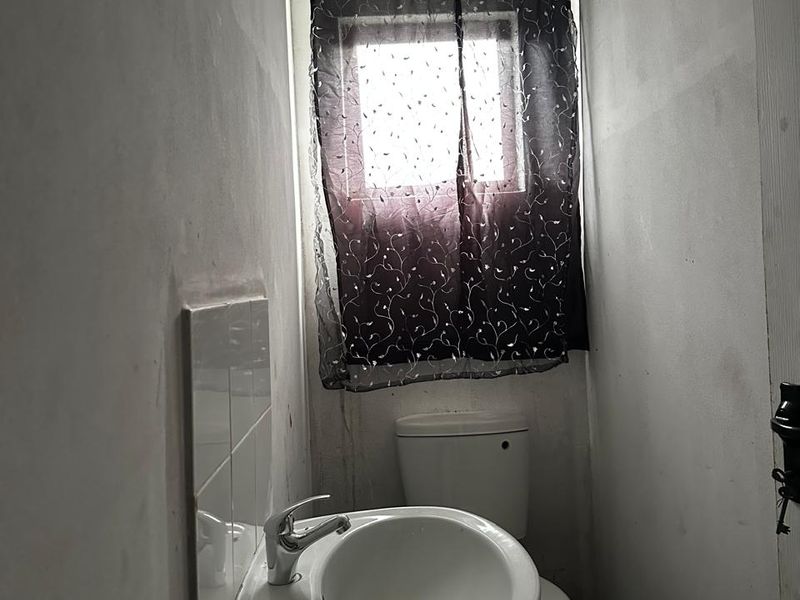 A small, compact bathroom featuring a pedestal basin and toilet, currently requiring wall finishing and cosmetic updates to improve the overall aesthetic.