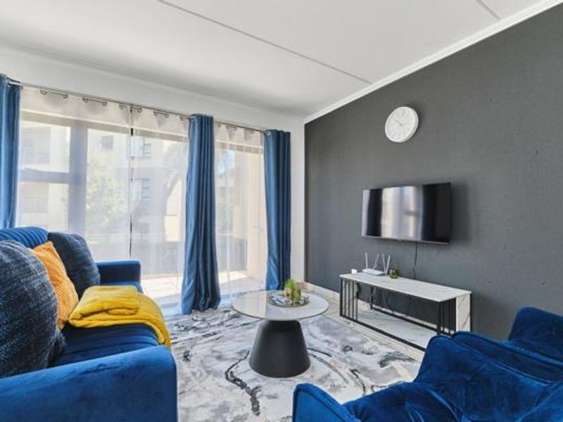 A bright living room featuring a dark accent wall, large sliding glass doors providing natural light, and modern finishes.