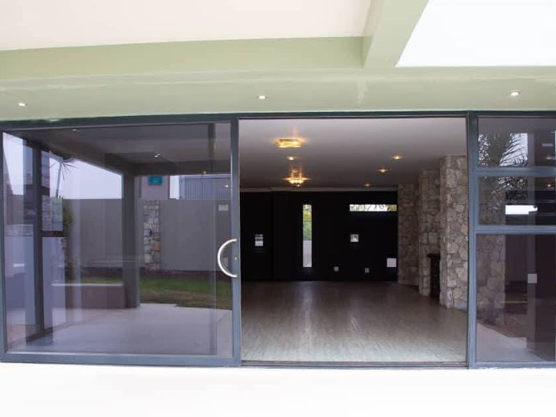 A covered patio area featuring large sliding glass doors, stone cladding accents, and recessed lighting, providing a seamless transition to the interior living space.