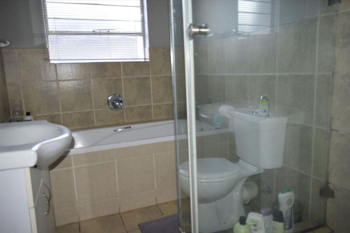 A functional bathroom featuring a built-in bathtub, a separate glass-enclosed shower, and a pedestal basin with neutral wall tiling.