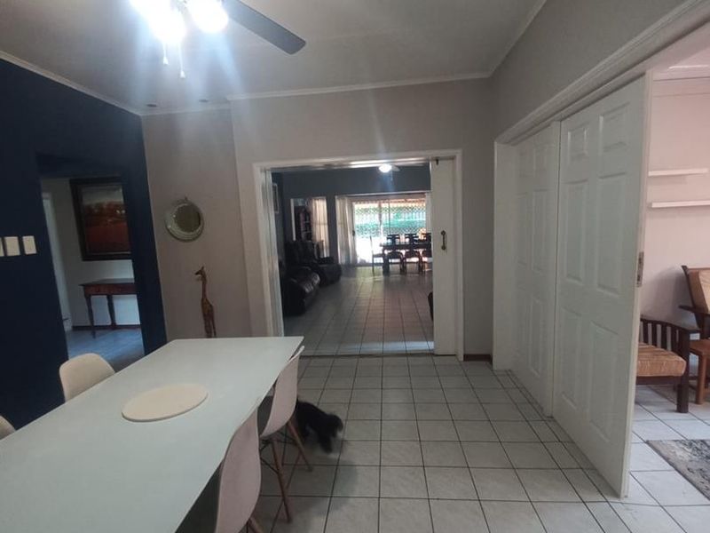 Dining area featuring tiled flooring, a ceiling fan, and double sliding doors leading to an adjacent living space.