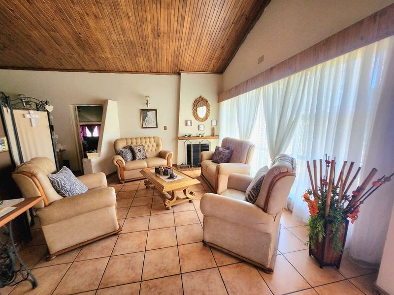 Spacious living room featuring a vaulted timber ceiling, tiled flooring, and a central built-in fireplace, offering a warm and traditional atmosphere.