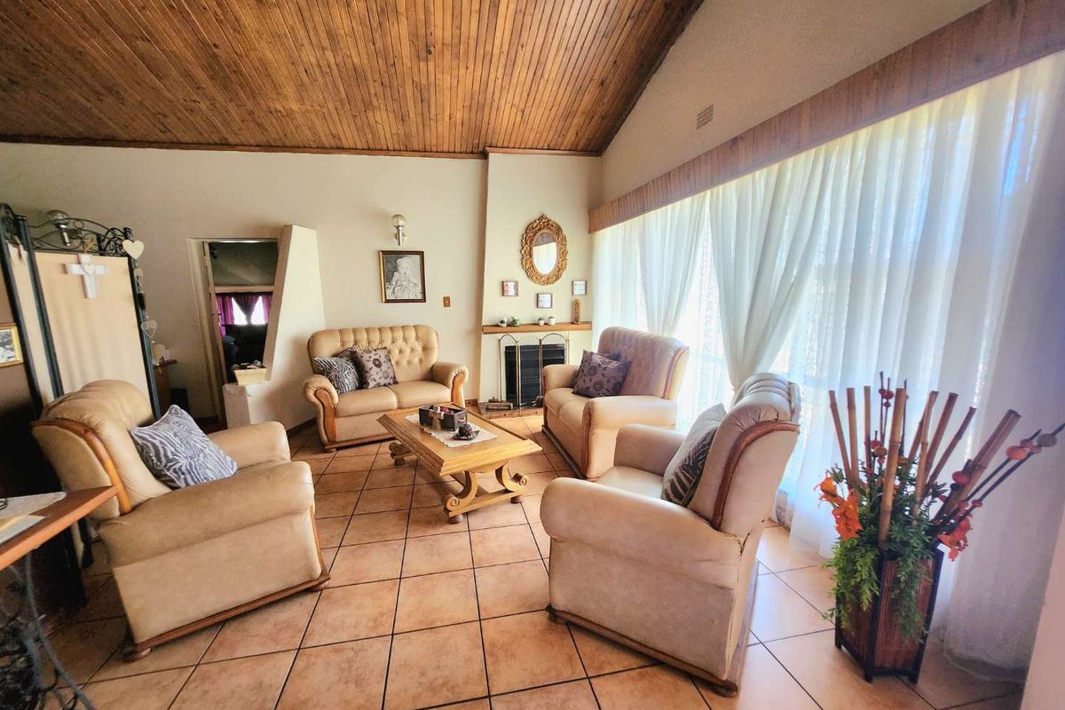 Spacious living room featuring a vaulted timber ceiling, tiled flooring, and a central built-in fireplace, offering a warm and traditional atmosphere.