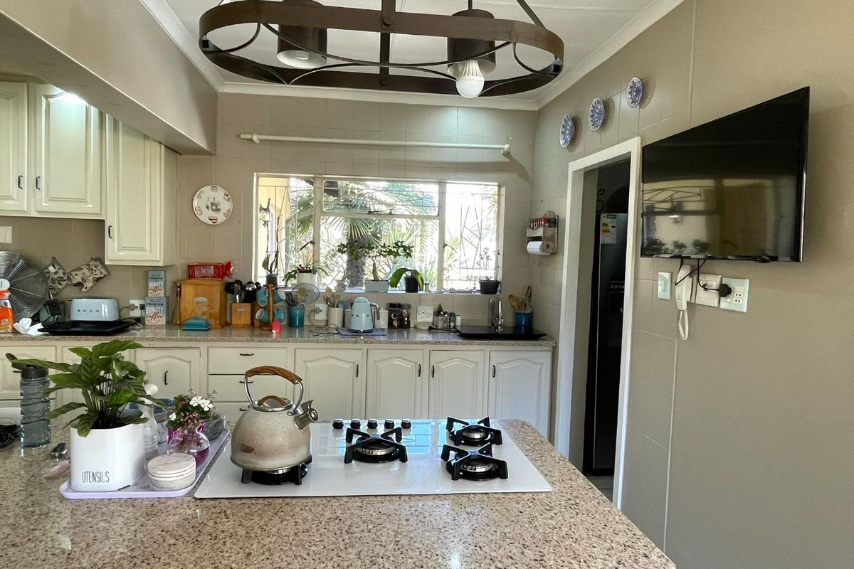 A functional kitchen featuring a central island with a built-in gas hob, granite countertops, and white cabinetry, offering a practical layout for daily cooking.