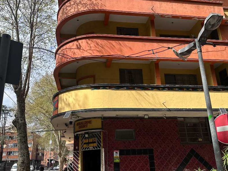 Exterior view of Geraldine Court apartment building featuring a multi-story facade with balconies and ground-level tiled entrance.
