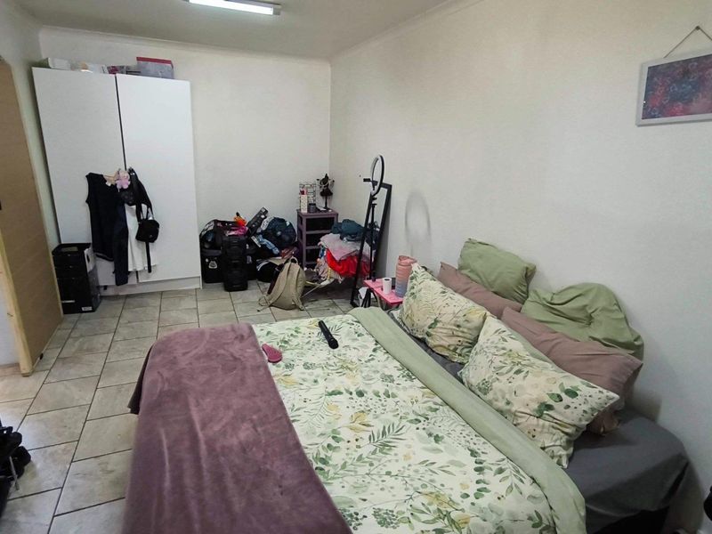 A bedroom featuring tiled flooring and a built-in wardrobe, offering a functional space with potential for cosmetic updates.