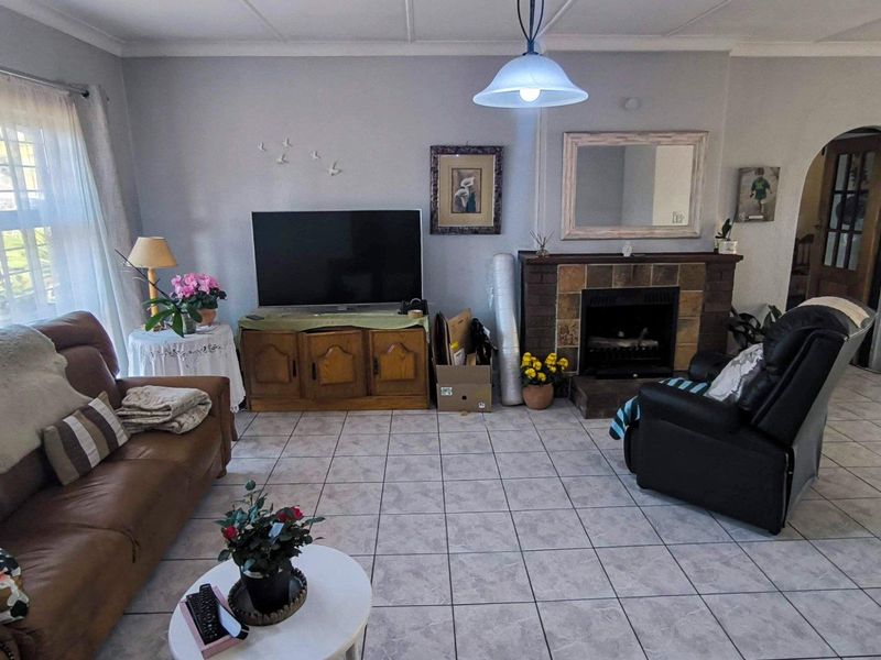 A living room featuring tiled flooring, a built-in fireplace, and an arched doorway leading to adjacent living spaces.