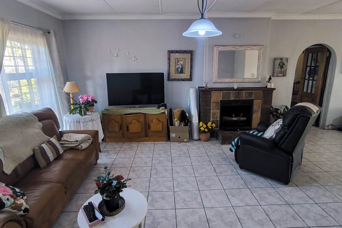 A living room featuring tiled flooring, a built-in fireplace, and an arched doorway leading to adjacent living spaces.