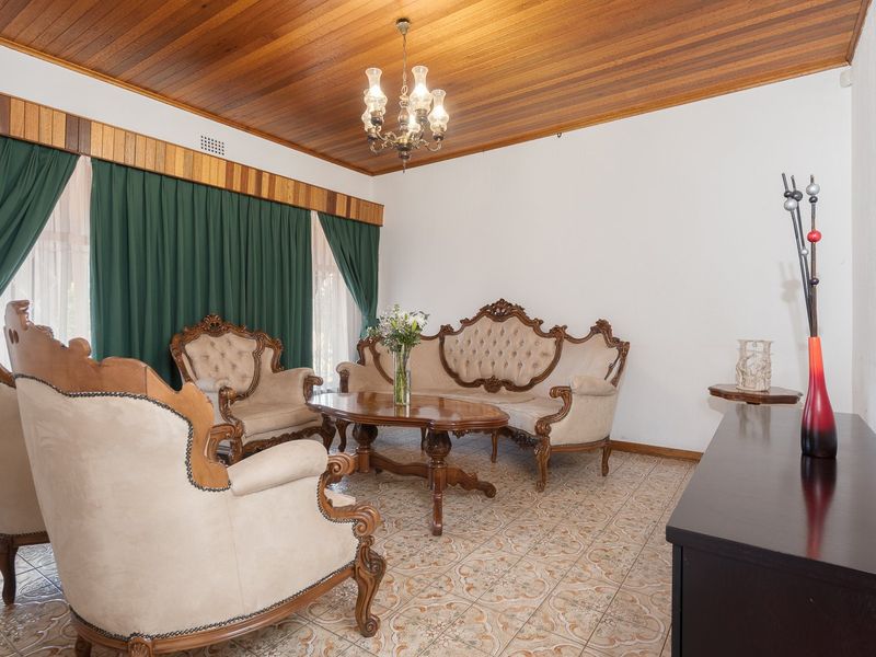 A formal living room featuring a distinctive timber-clad ceiling, ceramic tiled flooring, and a classic chandelier, offering a traditional aesthetic.